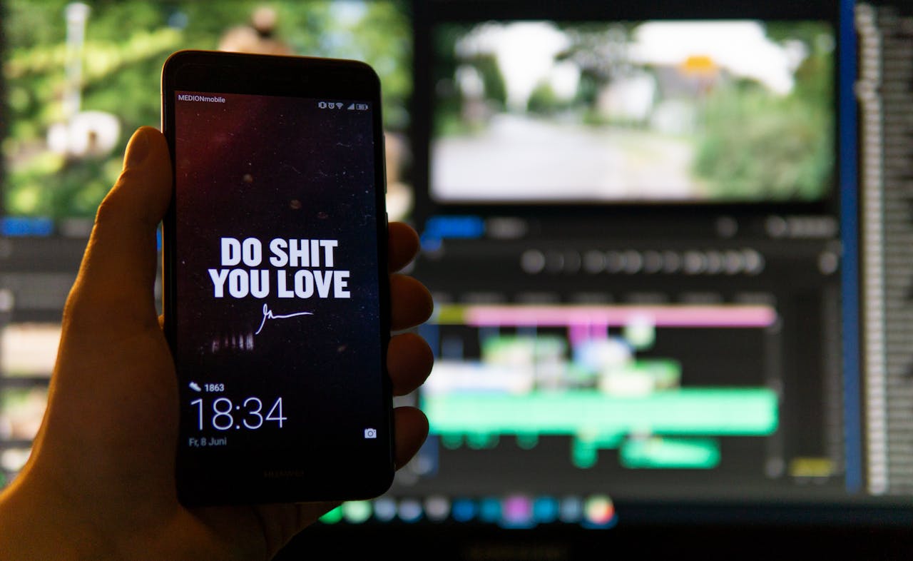 Close-up of a smartphone displaying an inspirational message against a video editing background.