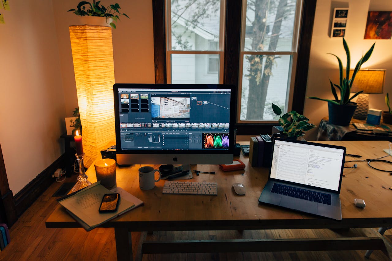 A cozy home office setup featuring a laptop, monitor, and warm lighting, perfect for remote work.